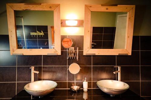 a bathroom with two sinks and two mirrors at Bij de Zöster in Kinrooi