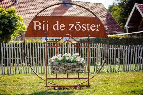 a sign with a basket of flowers in a yard at Bij de Zöster in Kinrooi