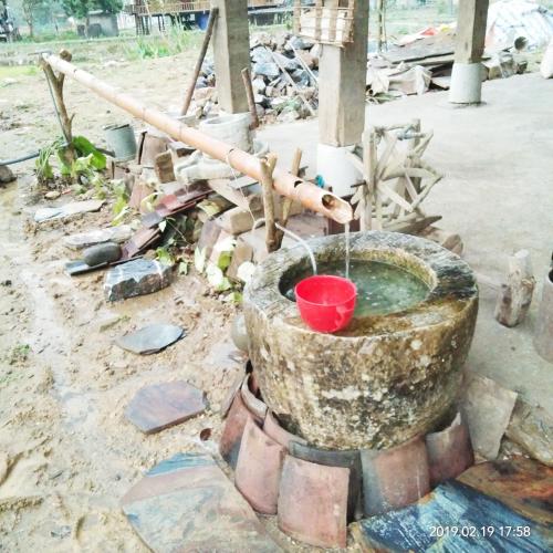 a fountain in the dirt with a red bucket at Tày Cốc Pảng Homestay in Làng Cac