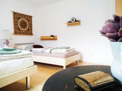Zimmer mit 2 Betten und einem Tisch mit Vase in der Unterkunft Dimai House No 16 Dornbirn Zentrum in Dornbirn