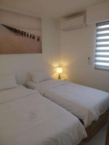 deux lits dans une chambre blanche avec une fenêtre dans l'établissement Appartement l'Estaque, à Nice
