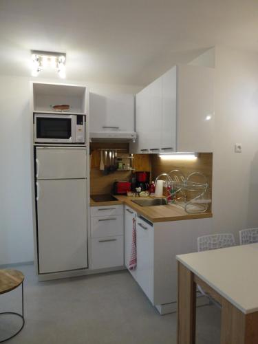 une cuisine avec des armoires blanches et un réfrigérateur blanc dans l'établissement Appartement l'Estaque, à Nice
