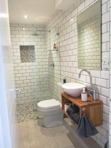 a bathroom with a sink and a toilet and a mirror at Stonebrook Apartments in Simonʼs Town