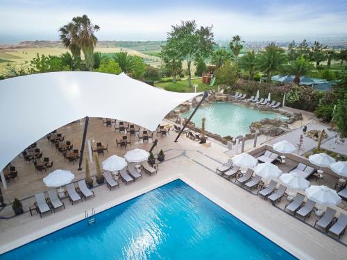uma vista sobre a piscina num resort com cadeiras brancas e uma piscina em Richmond Pamukkale Thermal em Pamukkale