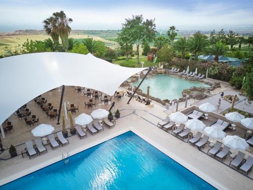 una vista aérea de la piscina en un complejo con sillas blancas y una piscina en Richmond Pamukkale Thermal, en Pamukkale