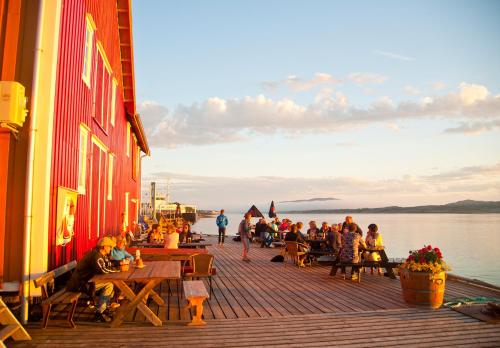a group of people sitting at tables on a boardwalk at Handelsstedet Forvik in Vevelstad