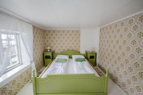 a green bed in a small room with a window at Handelsstedet Forvik in Vevelstad