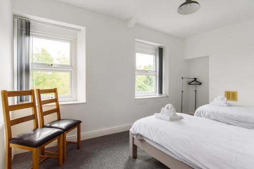 a bedroom with a bed and a chair and two windows at Railway Cottage in Newport
