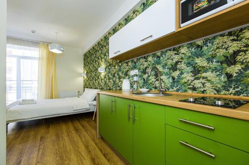 een keuken met groene kasten en een bed in een kamer bij BonApart Delux in Lviv