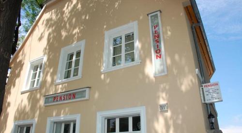 ein gelbes Gebäude mit weißen Fenstern und Schildern darauf in der Unterkunft Pension Am Werder in Bernburg
