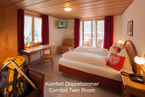 ein Schlafzimmer mit einem Bett und einem Schreibtisch in einem Zimmer in der Unterkunft Hotel Hirschen - Grindelwald in Grindelwald