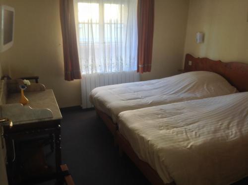 a bedroom with two beds and a table and a window at Hôtel Restaurant Zum Schnogaloch in Obernai