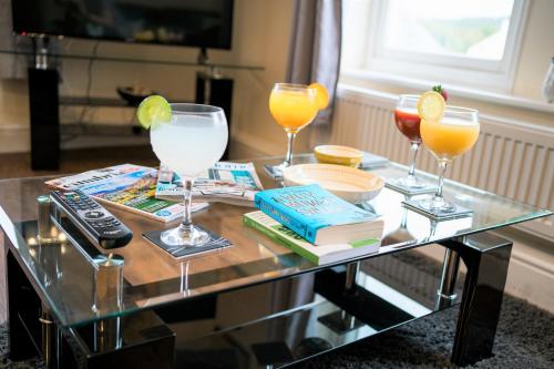 a glass coffee table with three glasses of orange juice at Irene Court Cockermouth in Cockermouth