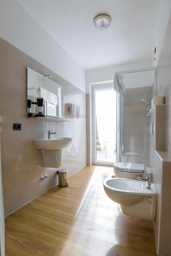 a white bathroom with a sink and a toilet at Hotel Ristorante Miravalle in Teglio