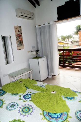 a room with a bed with a green rug on the floor at Pousada Irashai in Juquei
