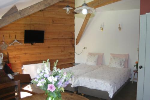 a bedroom with a bed and a tv on the wall at B&B De Leeghpoel in Rumpt