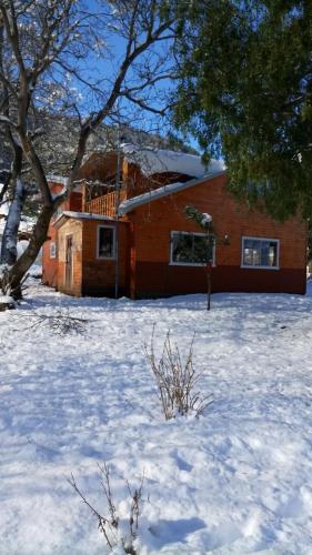 a house in the snow in front of a building at Turismo Rural Los Alpes in Futaleufú