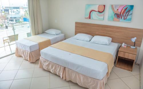 ein Hotelzimmer mit 2 Betten und einem Fenster in der Unterkunft Hotel QualitySul in Teixeira de Freitas