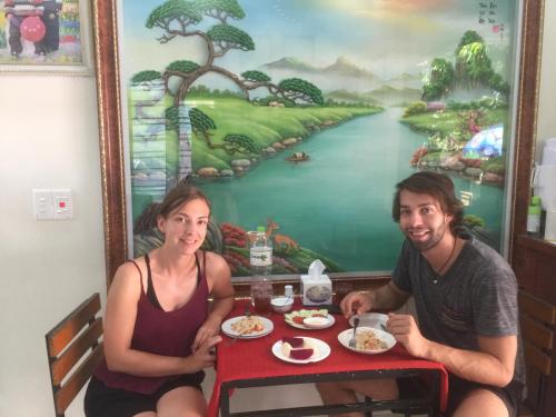 a man and a woman sitting at a table with food at Cat Ba Mystery Homestay in Cat Ba