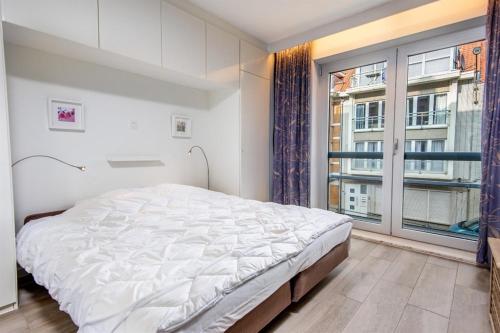 ein Schlafzimmer mit einem Bett und einem großen Fenster in der Unterkunft Strandvakantieappartement Zilverstrand - met binnenzwembad! in De Haan