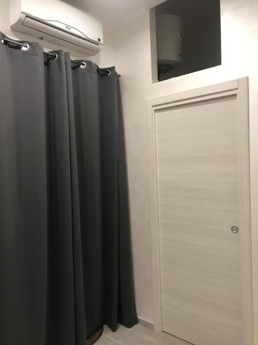 a bathroom with a black shower curtain and a door at La Maison Doppia in Stornara