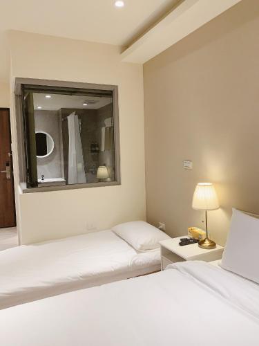 a hotel room with two beds and a mirror at In Fengchia in Taichung