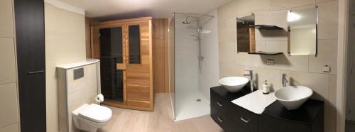 een badkamer met 2 wastafels, een douche en een toilet bij Vivere in Aan de Wolfsberg