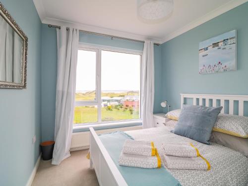 ein Schlafzimmer mit einem Bett und einem großen Fenster in der Unterkunft Seacoast Cottage in Castlerock