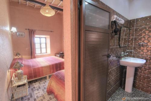 a bathroom with a shower and a sink and a bed at La Porte du Dades in Boumalne