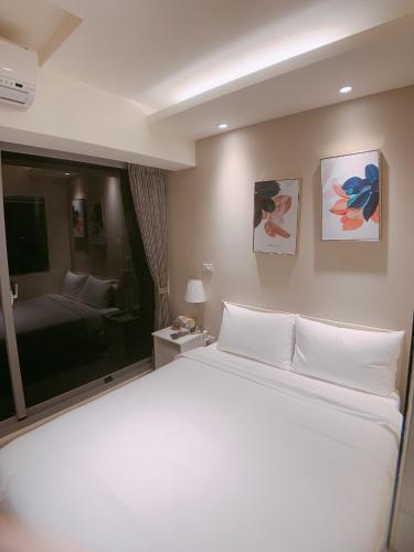 a bedroom with a white bed and a living room at In Fengchia in Taichung