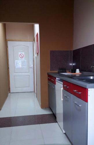 a kitchen with red cabinets and a white door at Hostel Paparazzo & Apartmens in Kikinda