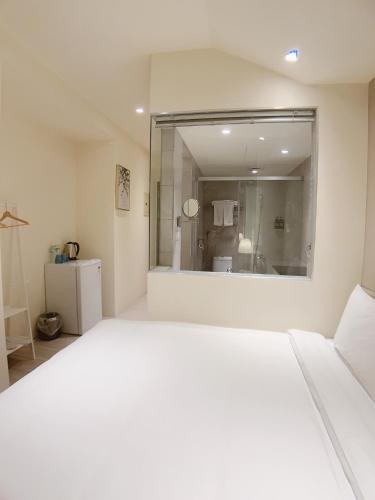 a white bedroom with a large mirror and a bathroom at In Fengchia in Taichung