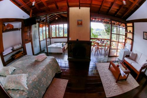 a bedroom with a large bed and a living room at Pousada Vida Verde in Gonçalves
