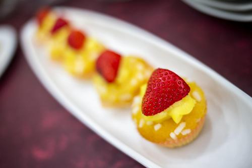 a white plate with three deserts with a strawberry on it at Santa Caterina Hotel & Bike in Chianciano Terme