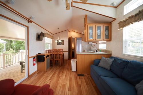Bethpage Three-Bedroom Cottage 15 في Urbanna: غرفة معيشة مع أريكة زرقاء ومطبخ