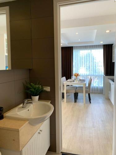 a bathroom with a sink and a dining room with a table at Exclusive Garden View 1 bedroom suite @Patio Bangsaen in Bangsaen