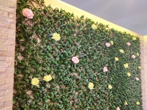 a green hedge with pink and yellow flowers on it at Hotel De Sripoom in Chiang Mai