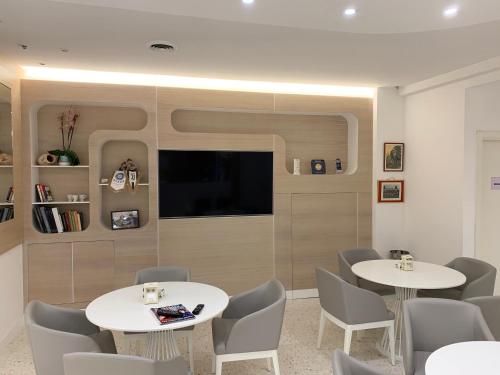 ein Wartezimmer mit Tischen und Stühlen und einem Flachbild-TV in der Unterkunft Hotel San Carlo in Lignano Sabbiadoro