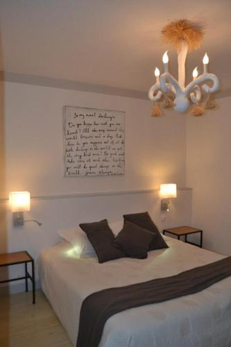 a bedroom with a large bed with a chandelier at Appart's Village Trama Loges in Puymirol