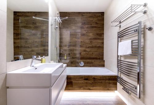 een badkamer met een witte wastafel en een bad bij HOTEL PECR DEEP in Pec pod Sněžkou