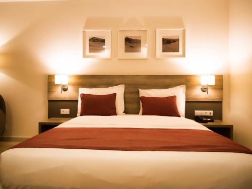 a bedroom with a large bed with red pillows at Hotel Monotel Dar El Barka in Nouakchott