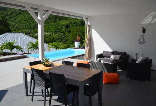 a patio with a table and chairs and a pool at Villa Coco Cannelle in Deshaies