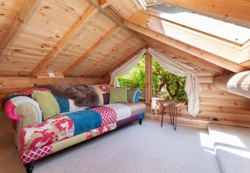 um quarto com um sofá num sótão de madeira em Porthole Log Cabin em Minehead