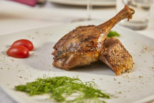 a piece of meat on a white plate with tomatoes at Santa Caterina Hotel & Bike in Chianciano Terme