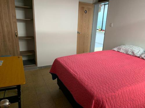 a bedroom with a bed with a red comforter at Casa Tuvia in Medellín