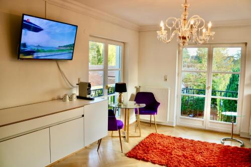 un soggiorno con TV, tavolo e sedie di Villa am Steinhuder Meer Superior DZ-Azur- mit kl Pantry Küche, Garten, WLAN a Steinhude