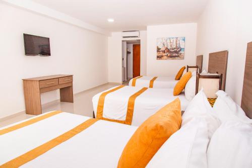 Habitación de hotel con 3 camas y escritorio. en Sol Caribe San Andrés All Inclusive, en San Andrés
