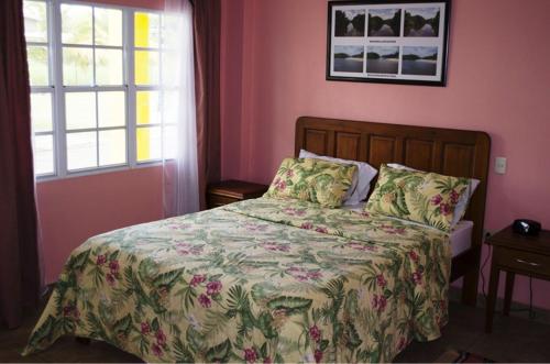 a bedroom with a bed with a green and pink comforter at Piarco Village Suites in Piarco