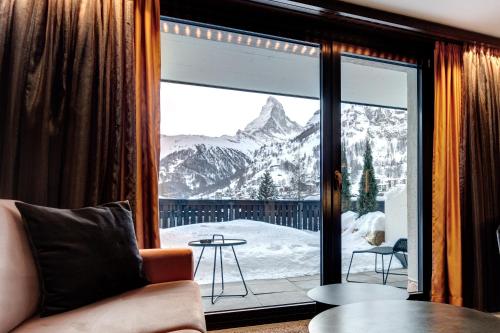 a room with a window with a view of a mountain at The Christiania Mountain & Spa Resort in Zermatt