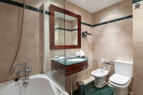 
a bathroom with a toilet, sink, tub and shower at Exe Laietana Palace in Barcelona
